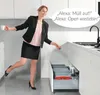 A woman in a kitchen is using a voice-activated waste bin opener. Produktbild-Vorschau