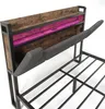 A close-up view of a bed frame with a headboard featuring wood and pink accents, and a gray upholstered element extended. Anteprima dell’immagine prodotto