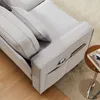 A close-up view of a gray sofa with side pockets holding a phone and a magazine, next to a small round side table. Produktbild-Vorschau