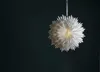 A white paper star ornament hangs against a dark green background. Podgląd zdjęcia produktu