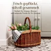 A wicker basket filled with flowers and herbs sits on a patterned floor in front of a cabinet. Náhľad obrázku produktu