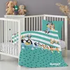 A Bluey-themed baby bedding set is displayed in a white crib, with stuffed animals on a shelf above. Produktbild-Vorschau