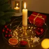 A festive Christmas arrangement with a lit candle, fairy lights, ornaments, and a gift box. Produktbild-Vorschau