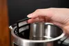 A hand is holding a filter over the opening of a kettle. Podgląd zdjęcia produktu