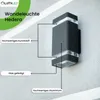 A black outdoor wall light is mounted on a textured gray wall, with lines pointing to different parts of the light and labels describing the materials. Produktbild-Vorschau