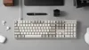 A top-down view of a desk setup with a keyboard, mouse, pen, and other accessories. Produktbild-Vorschau