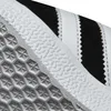 A close-up view of the sole and side of a sneaker, showing the textured grip pattern and the iconic three stripes. Produktbild-Vorschau