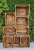 A stack of wooden crates against a green leafy background. Náhled obrázku produktu
