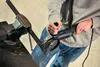 A person is using an angle grinder to cut a metal bar clamped in a vise. Náhled obrázku produktu