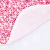 A close-up view of a pink floral fabric with a white border, suggesting it's part of a product like an apron or bib. Produktbild-Vorschau