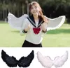 A woman wearing white angel wings and a school uniform, with a separate collage of black and white angel wings. Produktbild-Vorschau