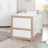 A baby crib with white bedding and pillows, placed in a room with a wardrobe and a rug. Anteprima dell’immagine prodotto
