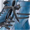 A close-up view of the laces and eyelets of a pair of blue leather boots. Voir les images du produit