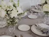 A beautifully set table with white floral arrangements and elegant tableware, suggesting a formal dining occasion. Produktbild-Vorschau