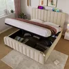 A bedroom scene with a bed that has its storage compartment open, revealing stored items. There are also electronic devices charging on the headboard. Produktbild-Vorschau