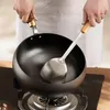 A person is holding a wok and a spatula over a stovetop. Produktbild-Vorschau
