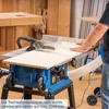 A person is using a blue table saw in a workshop setting. Produktbild-Vorschau