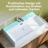 A white ceramic sink with a chrome faucet is shown on a countertop, with green tiled backsplash behind it. The sink has a decorative blue striped pattern on its edges. Produktbild-Vorschau