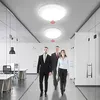 Three people in business attire walking down a modern office hallway with ceiling lights. Náhľad obrázku produktu