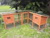 A wooden chicken coop with an attached run is set up on a grassy lawn. Produktbild-Vorschau