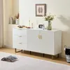 A white sideboard with gold accents is displayed in a well-lit room, with decorative items on top and a book on the floor in front. Produktbild-Vorschau