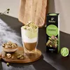 A layered coffee drink with pistachios and chocolate, next to a box of Tchibo Cafissimo espresso capsules. Podgląd zdjęcia produktu
