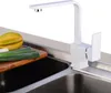 A white kitchen faucet is shown above a sink with some vegetables on a cutting board. Produktbild-Vorschau