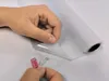 A person's hands are peeling a protective film off a roll of frosted window film. Podgląd zdjęcia produktu