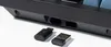 A close-up view of two USB dongles in front of a black keyboard. Produktbild-Vorschau