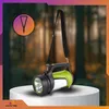 A flashlight with a strap is displayed on a white pedestal in front of a blurred forest background. A circular graphic with a lanyard icon is in the upper left corner. Podgląd zdjęcia produktu