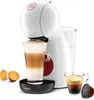 A white Nescafe Dolce Gusto coffee machine is shown in a studio shot, with a glass of latte, a shot of espresso, and coffee pods arranged around it. Produktbild-Vorschau
