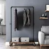 A clothing rack with clothes and boxes on it, next to a sofa in a room. Náhled obrázku produktu