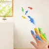 Eine Hand wirft bunte klebrige Dinosaurierspielzeuge auf eine helle Wand, einige kleben bereits Produktbild-Vorschau