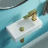 A close-up, high-angle shot of a small white wall-mounted sink with a gold faucet and drain. Anteprima dell’immagine prodotto