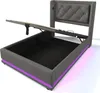 A grey upholstered bed frame with the mattress support lifted to reveal storage space underneath. Purple LED lights are visible along the base of the frame. Náhled obrázku produktu