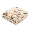 A folded cream-colored wool blanket with a brown floral pattern is shown against a white background. Produktbild-Vorschau