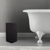 A black trash can is placed next to a white bathtub in a bathroom. Náhľad obrázku produktu
