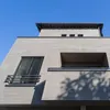 A close-up, low-angle shot of a modern building facade against a clear blue sky. Produktbild-Vorschau