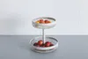 A two-tiered fruit basket filled with fruits on a countertop. Podgląd zdjęcia produktu