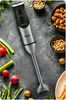 A hand blender is placed on a dark, textured surface surrounded by fresh vegetables and bowls of nuts. Náhľad obrázku produktu