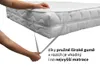 Hands adjusting elastic straps on a white quilted mattress protector on a mattress. Produktbild-Vorschau