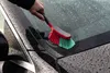 A hand is using a brush to clean a car windshield covered in water droplets. Produktbild-Vorschau