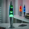 Three lava lamps are displayed on a shelf, with the closest one in focus. Produktbild-Vorschau