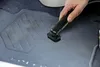 A hand is vacuuming the floor of a car with a black vacuum cleaner attachment. Podgląd zdjęcia produktu