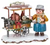 Ein fröhliches Winterkind in warmer Kleidung steht neben einem festlich geschmückten Punschwagen mit dampfendem Kessel und Tassen in der Hand bereit um heißen Punsch auszuschenken während Schnee auf dem Dach des Wagens liegt Produktbild-Vorschau