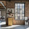 An interior shot of a room with exposed brick walls, a large industrial-style window, and several abstract paintings. A wooden display stand is in the foreground. Voir les images du produit