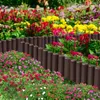 A garden border made of brown wooden-look stakes is separating a flower bed with various colorful flowers from the rest of the garden. Náhled obrázku produktu