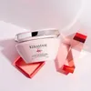 A pink Kérastase hair mask jar is displayed on a light pink surface with decorative pink and red geometric shapes. Náhled obrázku produktu