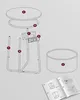 An exploded diagram of a round side table with integrated USB ports and a power outlet, showing its individual parts and assembly instructions. There is also an image of the assembled product and an open manual showing assembly steps. Produktbild-Vorschau