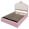 A pink upholstered bed frame with a crown-shaped headboard, shown from a diagonal angle. Podgląd zdjęcia produktu